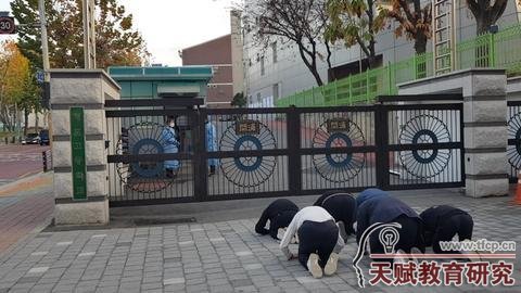 11月17日，韓國(guó)數(shù)名高中生在高考考場(chǎng)前磕頭應(yīng)援。（紐西斯通訊社）